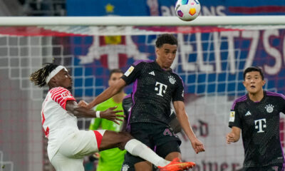 Bayern's Jamal Musiala, center, heads the ball pressured by Leipzig's Mohamed Simakan during the German Bundesliga soccer match between Leipzig and Bayern Munich, at the Red Bull Arena stadium in Leipzig, Germany, Saturday, Sept. 30, 2023. (AP Photo/Matthias Schrader)