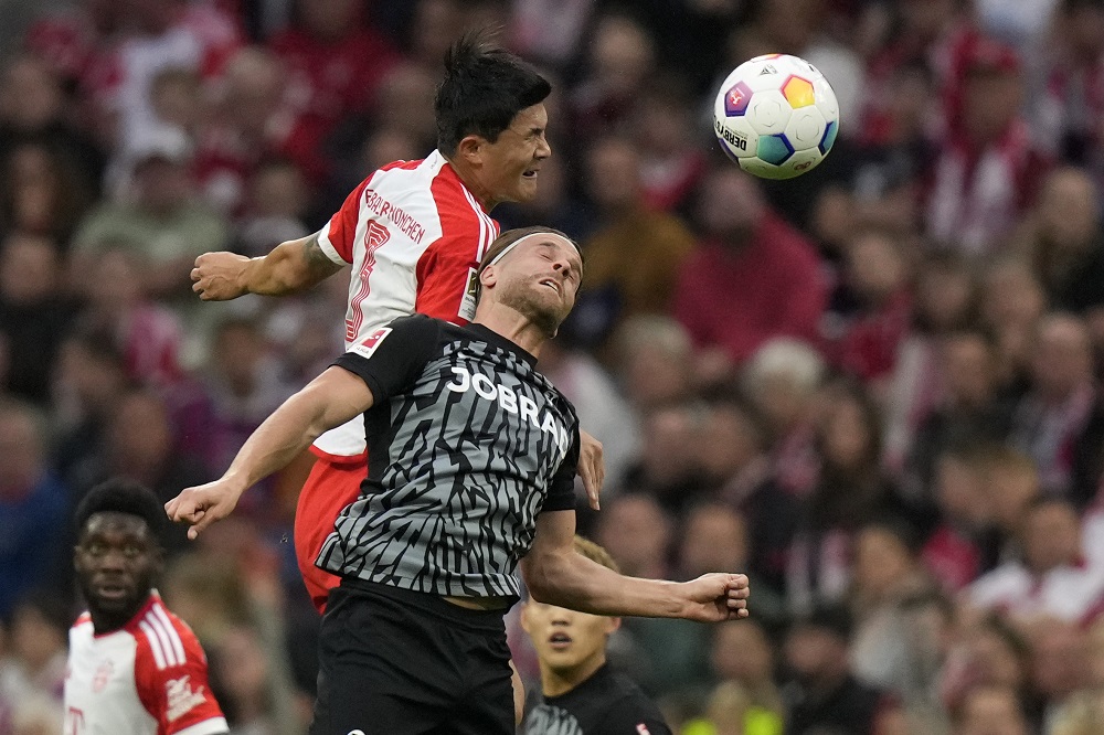 Bayern's Kim Min-jae, background, and Freiburg's Lucas Hoeler challenge for the ball during the German Bundesliga soccer match between FC Bayern Munich and SC Freiburg at the Allianz Arena stadium in Munich, Germany, Oct. 8, 2023. (AP Photo/Matthias Schrader)