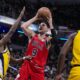 Chicago Bulls center Nikola Vucevic (9) shoots between Indiana Pacers forward Aaron Nesmith (23) and guard Buddy Hield (7) during the second half of an NBA basketball game in Indianapolis, Monday, Oct. 30, 2023. The Bulls defeated the Pacers 112-105. (AP Photo/Michael Conroy)