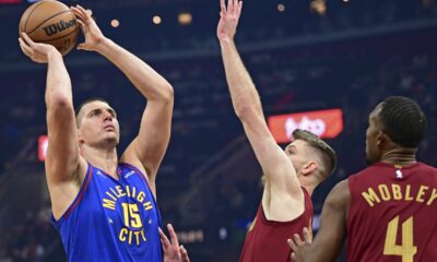 Denver Nuggets center Nikola Jokic, left, shoots against Cleveland Cavaliers forward Dean Wade, center, and forward Evan Mobley in the first half of an NBA basketball game, Sunday, Nov. 19, 2023, in Cleveland. (AP Photo/David Dermer)