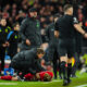 Liverpool's Kostas Tsimikas, bottom, grimaces in pain after a tackle by Arsenal's Bukayo Saka during the English Premier League soccer match between Liverpool and Arsenal at Anfield stadium in Liverpool, England, Saturday, Dec. 23, 2023. (AP Photo/Jon Super)