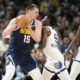 Denver Nuggets center Nikola Jokic, left, looks to drive to the basket as Memphis Grizzlies guard Vince Williams Jr., center, and forward Jaren Jackson Jr., right, defend in the second half of an NBA basketball game Thursday, Dec. 28, 2023, in Denver. (AP Photo/David Zalubowski)