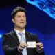 Former soccer player Brian Laudrup holds up the name Serbia during the draw for the UEFA Euro 2024 soccer tournament finals in Hamburg, Germany, Saturday, Dec. 2, 2023. (AP Photo/Martin Meissner)