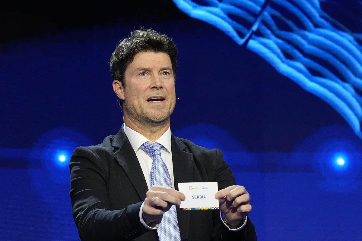 Former soccer player Brian Laudrup holds up the name Serbia during the draw for the UEFA Euro 2024 soccer tournament finals in Hamburg, Germany, Saturday, Dec. 2, 2023. (AP Photo/Martin Meissner)