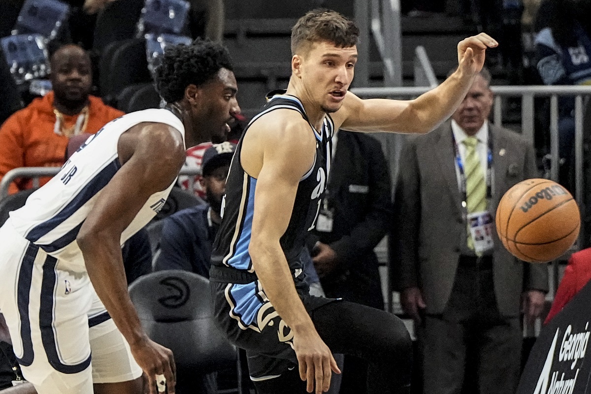 Atlanta Hawks guard Bogdan Bogdanovic (13) and Memphis Grizzlies guard Vince Williams Jr. (5) vie for a loose ball during the first half of an NBA basketball game, Saturday, Dec. 23, 2023, in Atlanta. (AP Photo/Mike Stewart)