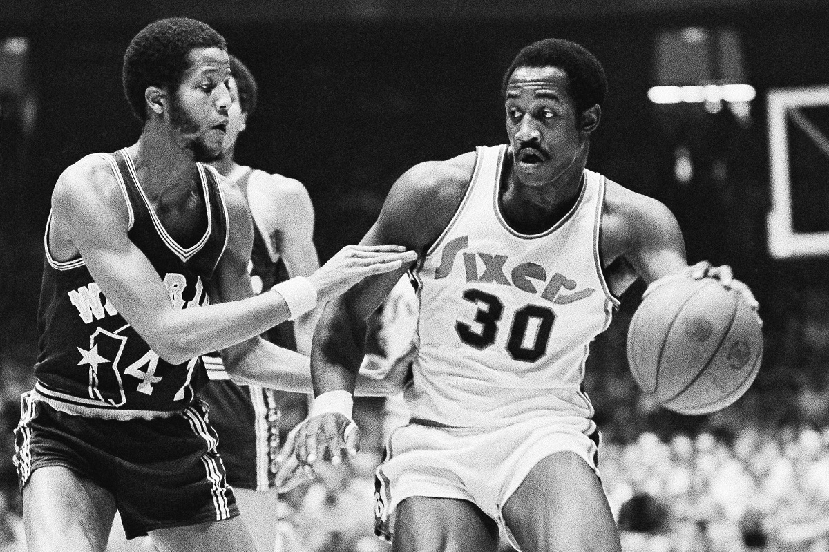 FILE - Golden State Warriors Jamaal Wilkes (41) tries to keep 76ers forward George McGinnis (30) from getting closer to the basket during the first half of NBA game on Tuesday, Nov. 25, 1975 in Philadelphia. McGinnis, a Hall of Fame forward who was a two-time ABA champion and three-time All-Star in the NBA and ABA, died Thursday, Dec. 14, 2023 He was 73. (AP Photo/Rusty Kennedy, File)