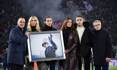 Family members hold a photo in remembrance of the one year anniversary of the death of Sinisa Mihajlovic, ahead of the Italian Serie A soccer match between Bolgna and Roma, at Renato Dall'Ara Stadium, in Bologna, Italy, Sunday, Dec. 17, 2023. (Massimo Paolone /LaPresse via AP)