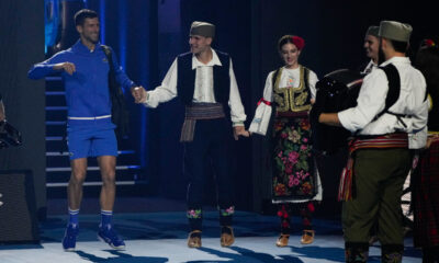 Serbia's Novak Djokovic reacts as he is greeted by dancers as walks onto Rod Laver Arena for an exhibition match against Stefanos Tsitsipas of Greece ahead of the Australian Open tennis championships at Melbourne Park, Melbourne, Australia, Thursday, Jan. 11, 2024. (AP Photo/Andy Wong)