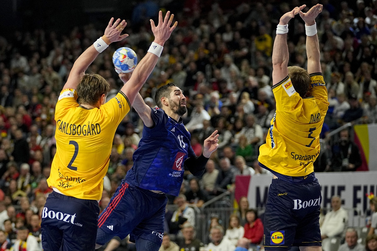 Sweden's Max Darj and Sweden's Jonathan Carlsbogard fail to prevent France's Nikola Karabatic from scoring during the Handball European Championship semifinal match between France and Sweden in Cologne, Germany, Friday, Jan. 26, 2024. (AP Photo/Martin Meissner)