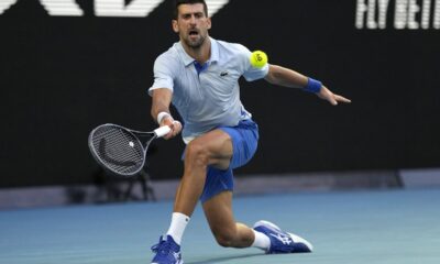 Novak Djokovic of Serbia plays a forehand return to Taylor Fritz of the U.S. during their quarterfinal match at the Australian Open tennis championships at Melbourne Park, Melbourne, Australia, Tuesday, Jan. 23, 2024. (AP Photo/Louise Delmotte)