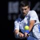 Novak Đoković of Serbia plays a backhand return to Taylor Fritz of the U.S. during their quarterfinal match at the Australian Open tennis championships at Melbourne Park, Melbourne, Australia, Tuesday, Jan. 23, 2024. (AP Photo/Andy Wong)