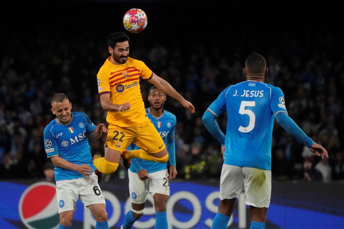 Barcelona's Ilkay Gundogan heads the ball besides Napoli's Mario Rui during the Champions League, round of 16, first leg soccer match between SSC Napoli and FC Barcelona at the Diego Maradona stadium in Naples, Italy, Wednesday, Feb. 21, 2024. (AP Photo/Gregorio Borgia)