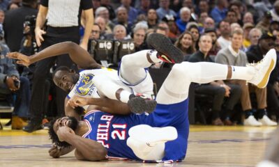 Golden State Warriors forward Draymond Green (23) falls over Philadelphia 76ers center Joel Embiid (21) on an offensive foul by Embiid during the first half of an NBA basketball game, Tuesday, Jan. 30, 2024, in San Francisco. (AP Photo/D. Ross Cameron)