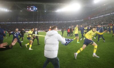 A Trabzonspor supporter swings a corner flag towards Fenerbahce's Mert Muldur, right, during clashes at the end of Turkish Super Lig soccer match between Trabzonspor and Fenerbahce at the Senol Gunes stadium in Trabzon, Turkey, Sunday, March 17, 2024. Clashes erupted between Trabzonspor fans and Fenerbahce players after local supporters stormed in the pitch at the end of the Turkish Super Lig match. (Huseyin Yavuz/Dia Images via AP)