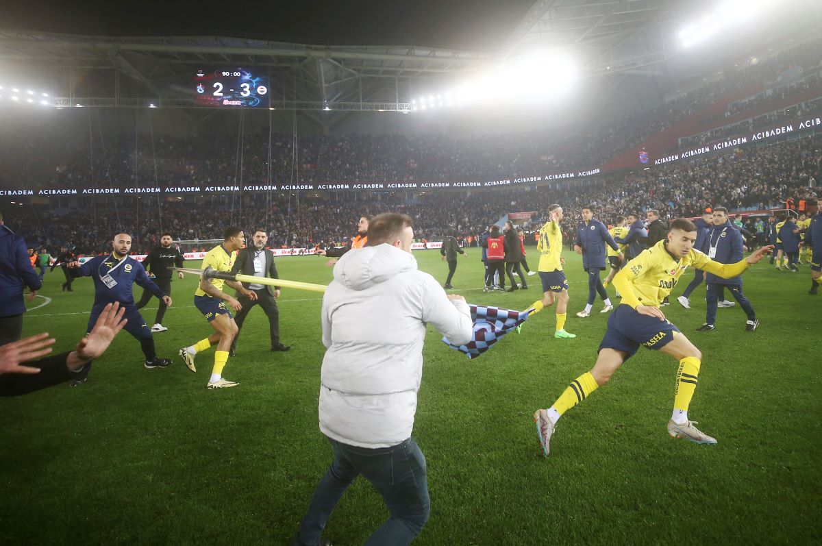 A Trabzonspor supporter swings a corner flag towards Fenerbahce's Mert Muldur, right, during clashes at the end of Turkish Super Lig soccer match between Trabzonspor and Fenerbahce at the Senol Gunes stadium in Trabzon, Turkey, Sunday, March 17, 2024. Clashes erupted between Trabzonspor fans and Fenerbahce players after local supporters stormed in the pitch at the end of the Turkish Super Lig match. (Huseyin Yavuz/Dia Images via AP)