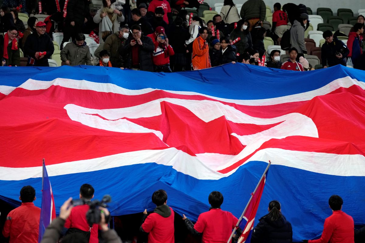 Supporters of North Korean team puts big North Korean flag prior to the FIFA World Cup 2026 and AFC Asian Cup 2027 preliminary joint qualification round 2 match between Japan and North Korea at the National Stadium at the National Stadium Thursday, March 21, 2024, in Tokyo. (AP Photo/Eugene Hoshiko)
