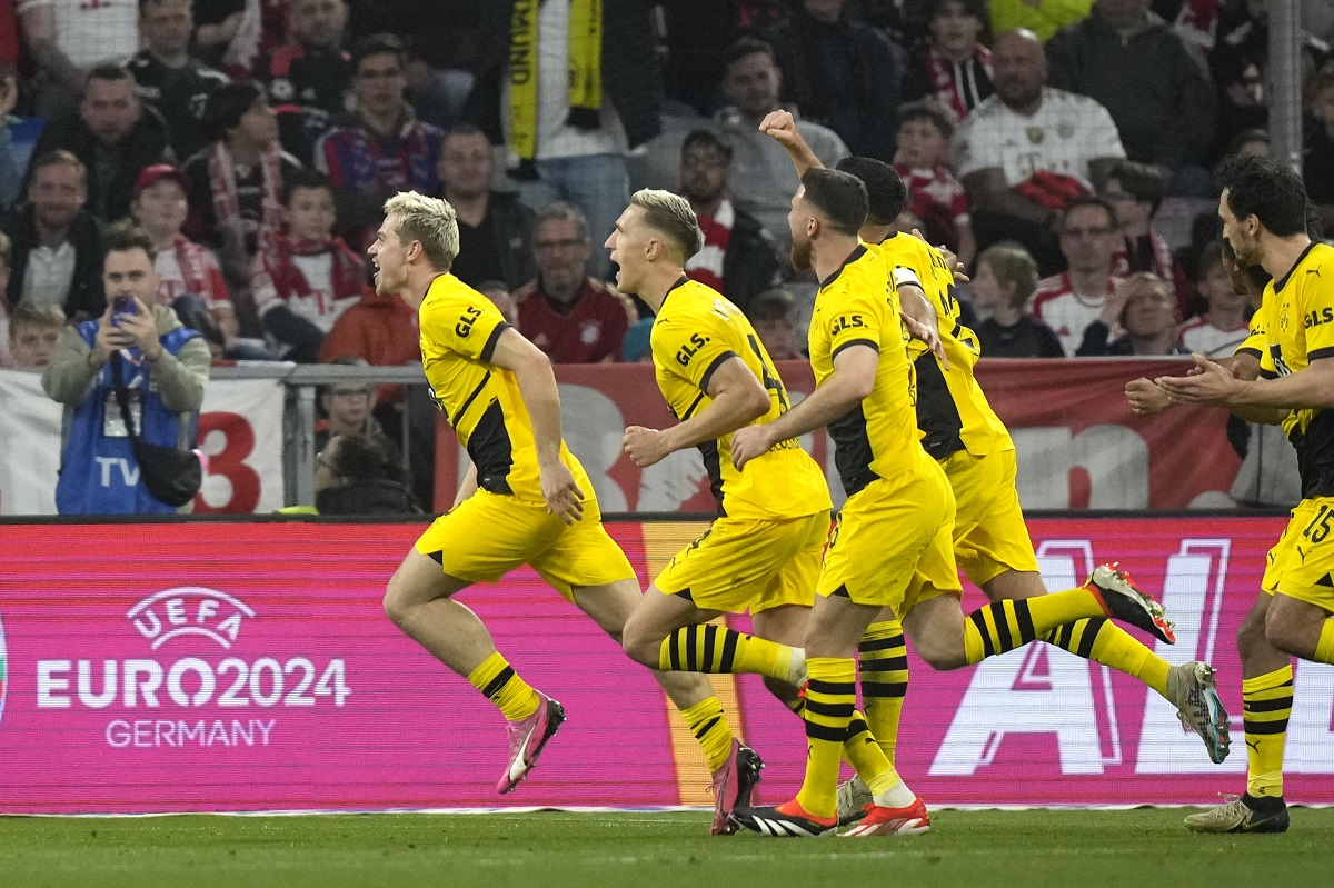 Dortmund's Julian Ryerson, left, celebrates after scoring his side's second goal during the German Bundesliga soccer match between FC Bayern Munich and Borussia Dortmund at the Allianz Arena stadium, in Munich, Germany, Saturday, March 30, 2024. (AP Photo/Matthias Schrader)