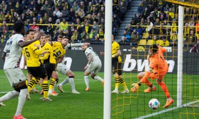 Leverkusen's Josip Stanisic, up, scores for his team in the last minute against Dortmund's goalkeeper Gregor Kobel, right, during the German Bundesliga soccer match between Borussia Dortmund and Bayer Leverkusen in Dortmund, Germany, Sunday, April 21, 2024. The match ended 1-1, Leverkusen is unbeaten since 45 matches. (AP Photo/Martin Meissner)