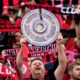 A supporter holds up a makeshift trophy ahead of the German Bundesliga soccer match between Bayer Leverkusen and Werder Bremen in Leverkusen, Germany, Sunday, April 14, 2024. Leverkusen could win the Bundesliga title if they win today's match against Werder Bremen.(AP Photo/Martin Meissner)