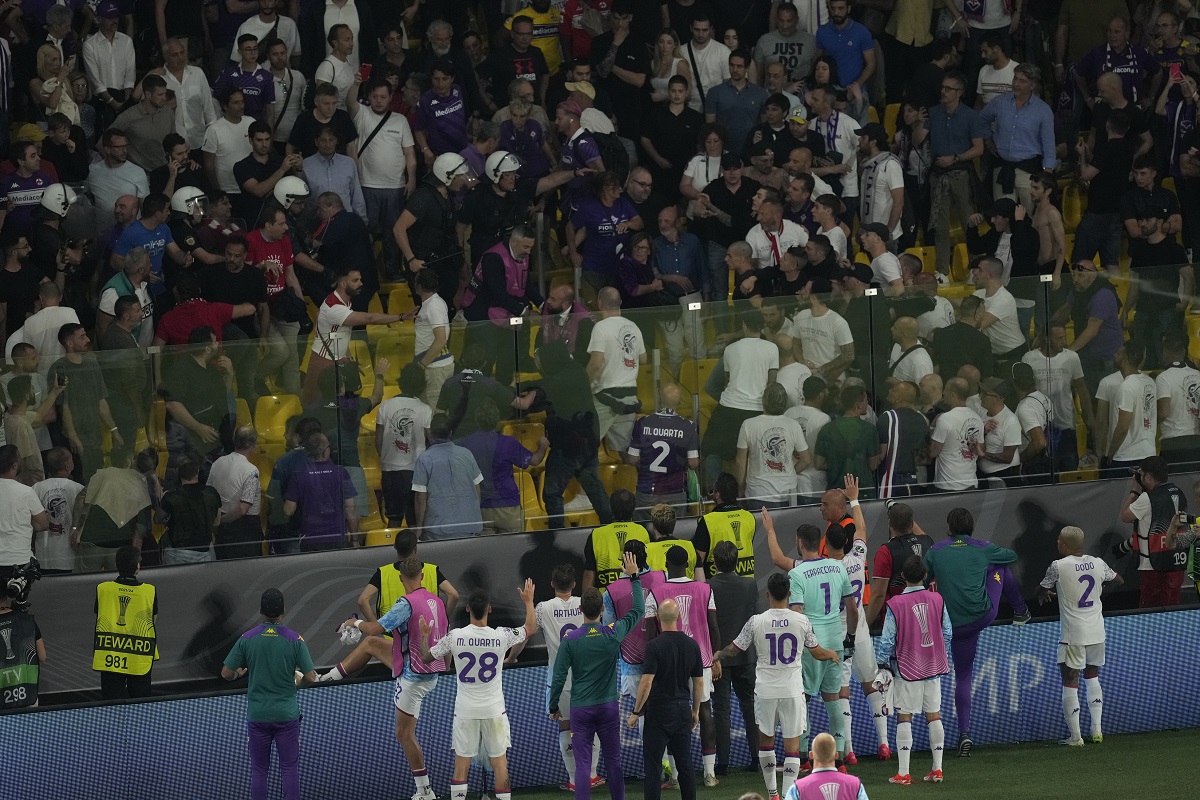 Fiorentina players try to deescalated during their supporters clashes with police at the half time during the Conference League final soccer match between Olympiacos FC and ACF Fiorentina at OPAP Arena in Athens, Greece, Wednesday, May 29, 2024. (AP Photo/Petros Karadjias)