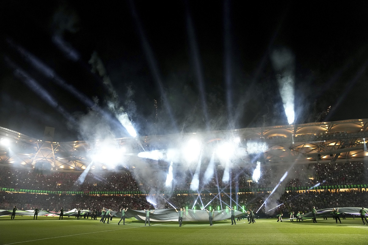Volunteers hold banners on the pitch before the Conference League final soccer match between Olympiacos FC and ACF Fiorentina at OPAP Arena in Athens, Greece, Wednesday, May 29, 2024. (AP Photo/Petros Giannakouris)