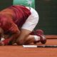 Two ball kids come to the aid of Serbia's Novak Djokovic after he slipped and fell during his fourth round match of the French Open tennis tournament against Argentina's Francisco Cerundolo at the Roland Garros stadium in Paris, Monday, June 3, 2024. (AP Photo/Thibault Camus)