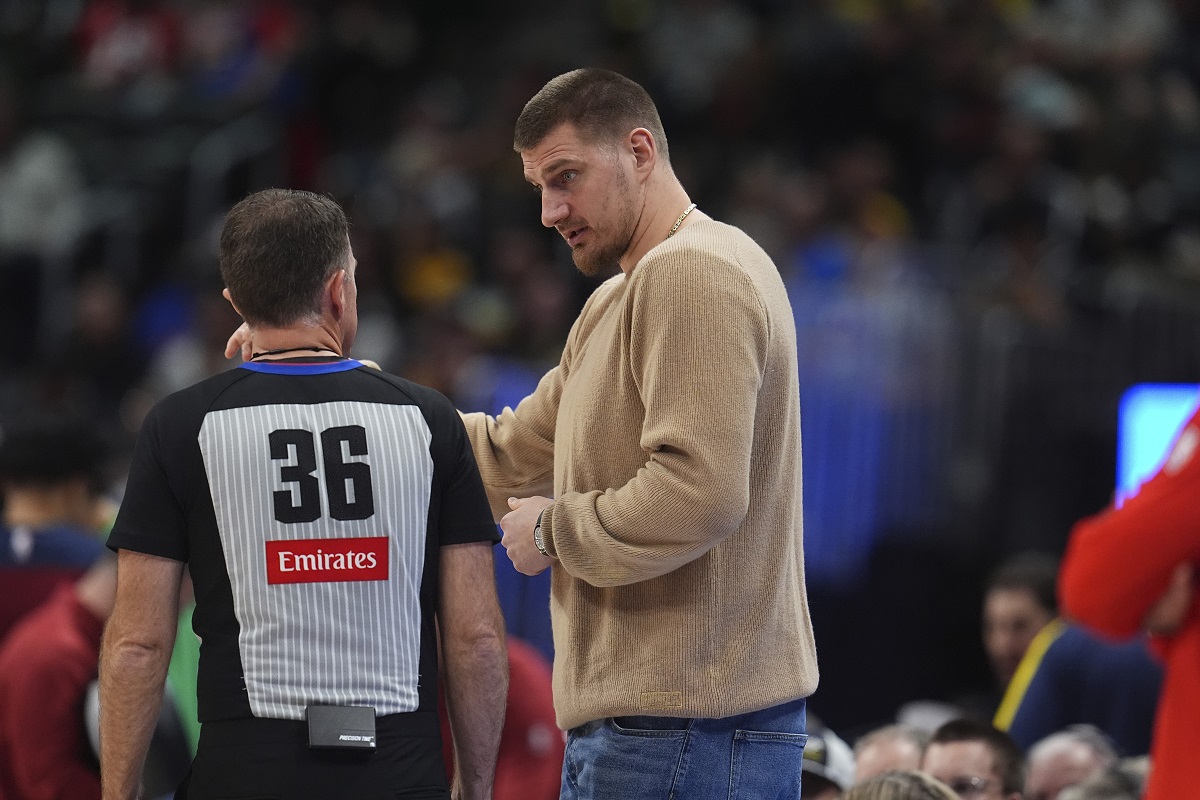 Injured Denver Nuggets center Nikola Jokic, center, confers with referee Brent Barnaky in the second half of an NBA basketball game against the Chicago Bulls, Monday, March 24, 2025, in Denver. (AP Photo/David Zalubowski)