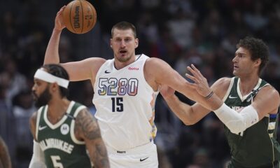 Denver Nuggets center Nikola Jokic, left, fields a pass as Milwaukee Bucks center Brook Lopez defends in the first half of an NBA basketball game Wednesday, March 26, 2025, in Denver. (AP Photo/David Zalubowski)