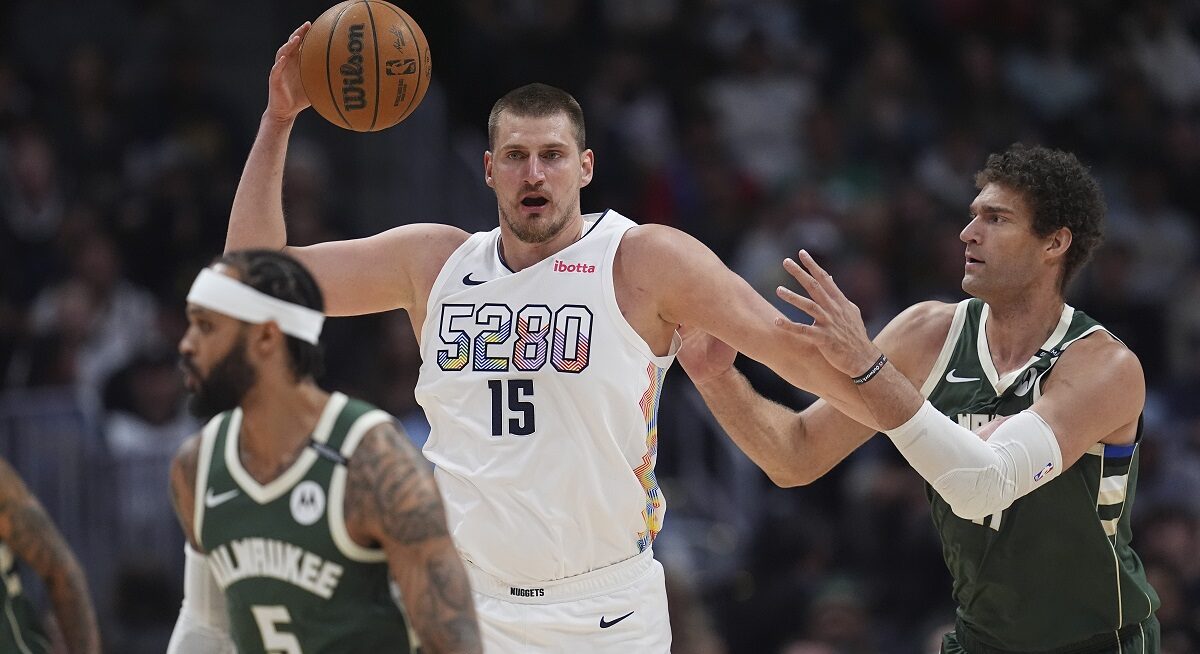 Denver Nuggets center Nikola Jokic, left, fields a pass as Milwaukee Bucks center Brook Lopez defends in the first half of an NBA basketball game Wednesday, March 26, 2025, in Denver. (AP Photo/David Zalubowski)