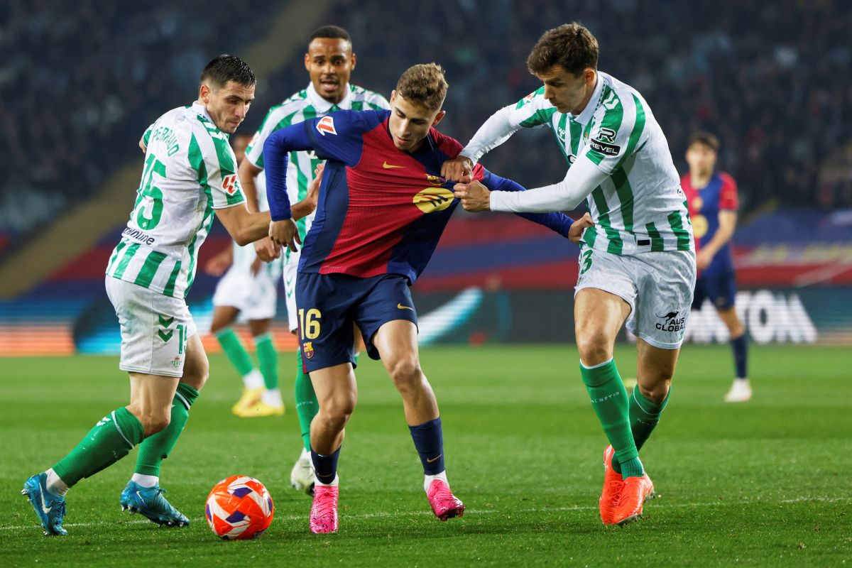 Barcelona's Fermin Lopez, center, is challenged by Betis' Romain Perraud, left, and Diego Llorente during a Spanish La Liga soccer match between Barcelona and Real Betis at the Lluis Companys Olympic stadium in Barcelona, Spain, Saturday, April 5, 2025. (AP Photo/Joan Monfort)