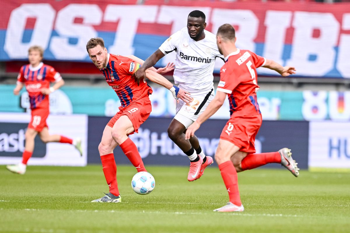Leverkusen's Victor Boniface, center, is caught between Heidenheim's Patrick Mainka, left, and Benedikt Gimber during the German Bundesliga soccer match between 1. FC Heidenheim and Bayer Leverkusen, at the Voith-Arena in Heidenheim, Germany, Saturday, April 5, 2025. (Harry Langer/dpa via AP)