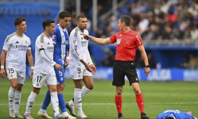 The referee speaks with Real Madrid's Kylian Mbappe, centre and other players as Alaves' Moussa Diarra lies on the ground during a Spanish La Liga soccer match between Alaves and Real Madrid at the Mendizorroza stadium in Vitoria, Spain, Sunday April 13, 2025. (AP Photo/Miguel Oses)