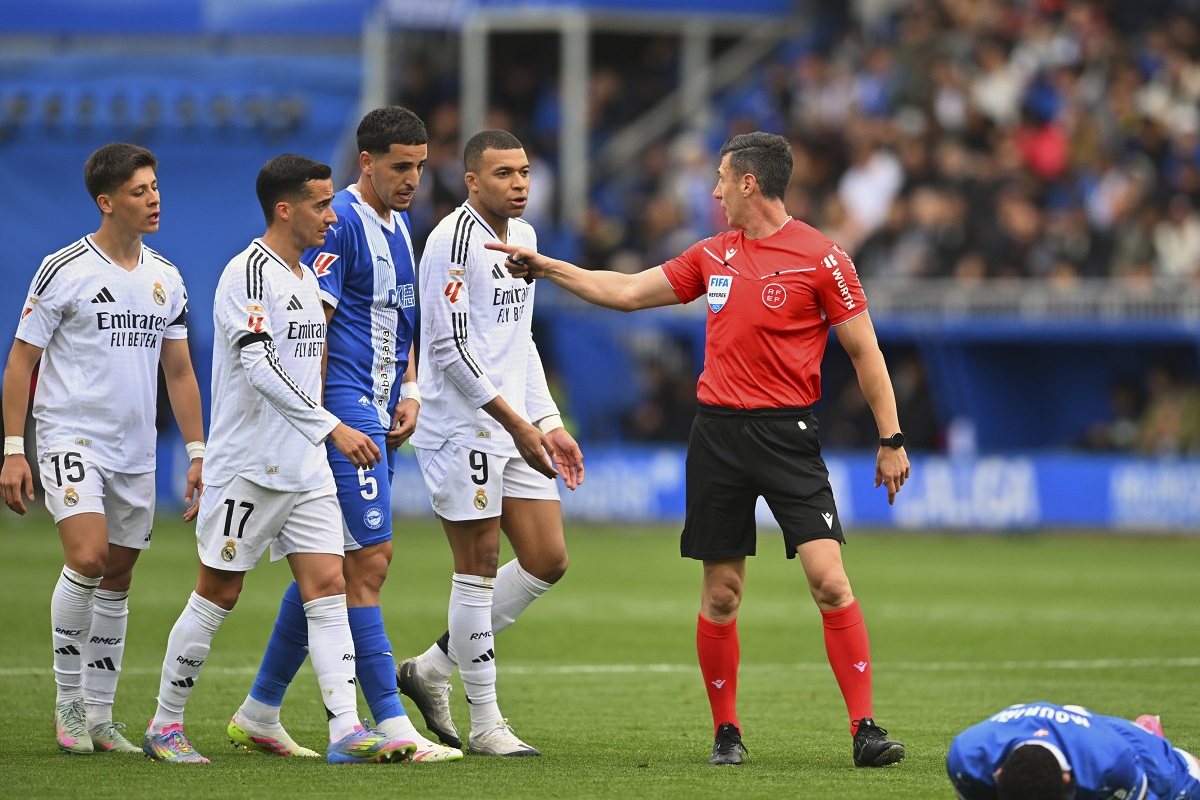 The referee speaks with Real Madrid's Kylian Mbappe, centre and other players as Alaves' Moussa Diarra lies on the ground during a Spanish La Liga soccer match between Alaves and Real Madrid at the Mendizorroza stadium in Vitoria, Spain, Sunday April 13, 2025. (AP Photo/Miguel Oses)