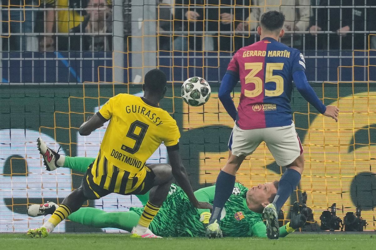 Barcelona's goalkeeper Wojciech Szczesny, center, makes a save in front of Dortmund's Serhou Guirassy, left, during the Champions League quarterfinals second leg soccer match between Borussia Dortmund and Barcelona, at the Signa-Iduna Park in Dortmund, Germany, Tuesday, April 15, 2025. (AP Photo/Martin Meissner)