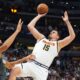 Denver Nuggets center Nikola Jokic, right, shoots for a basket over Minnesota Timberwolves center Rudy Gobert in the first half of an NBA basketball game Tuesday, April 1, 2025, in Denver. (AP Photo/David Zalubowski)