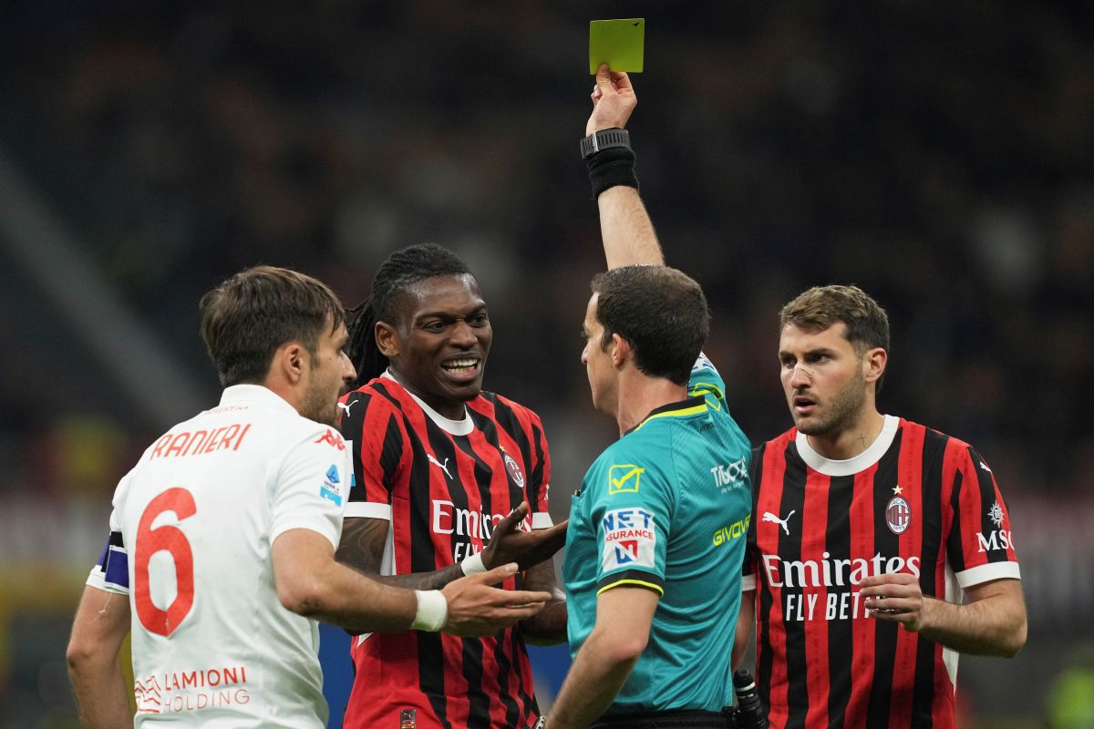 Referee Giovanni Ayroldi shows a yellow card to AC Milan's Rafael Leao during the Italian Serie A soccer match between AC Milan and Fiorentina at the San Siro Stadium in Milan, Italy, Saturday, April 5, 2025. (AP Photo/Antonio Calanni)