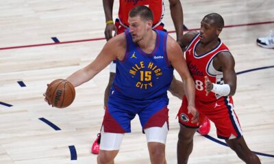 Denver Nuggets center Nikola Jokic, left, looks to pass the ball as Los Angeles Clippers guard Kris Dunn defends in the first half of Game 1 of an NBA first-round playoff series Saturday, April 19, 2025, in Denver. (AP Photo/David Zalubowski)