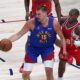 Denver Nuggets center Nikola Jokic, left, looks to pass the ball as Los Angeles Clippers guard Kris Dunn defends in the first half of Game 1 of an NBA first-round playoff series Saturday, April 19, 2025, in Denver. (AP Photo/David Zalubowski)