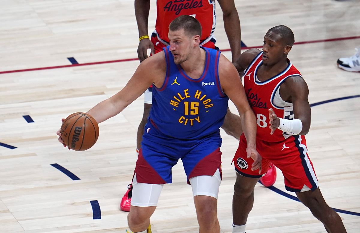 Denver Nuggets center Nikola Jokic, left, looks to pass the ball as Los Angeles Clippers guard Kris Dunn defends in the first half of Game 1 of an NBA first-round playoff series Saturday, April 19, 2025, in Denver. (AP Photo/David Zalubowski)