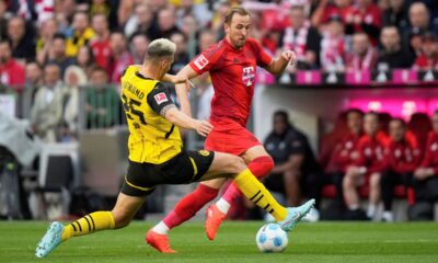 Dortmund's Niklas Suele, bottom left, challenges for the ball with Bayern's Harry Kane during the German Bundesliga soccer match between Bayern Munich and Borussia Dortmund at the Allianz Arena in Munich, Germany, Saturday, April 12, 2025. (AP Photo/Matthias Schrader)