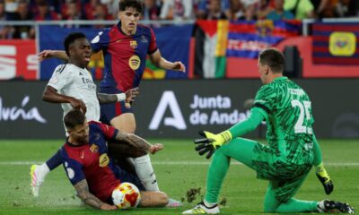 Real Madrid's Vinicius Junior, second left, fights for the ball with Barcelona's goalkeeper Wojciech Szczesny, right, Barcelona's Inigo Martinez, left, and Barcelona's Pau Cubarsi during the Spanish Copa del Rey final soccer match between Barcelona and Real Madrid at Estadio de La Cartuja stadium in Seville, Spain, Saturday, April 26, 2025. (AP Photo/Joan Monfort)