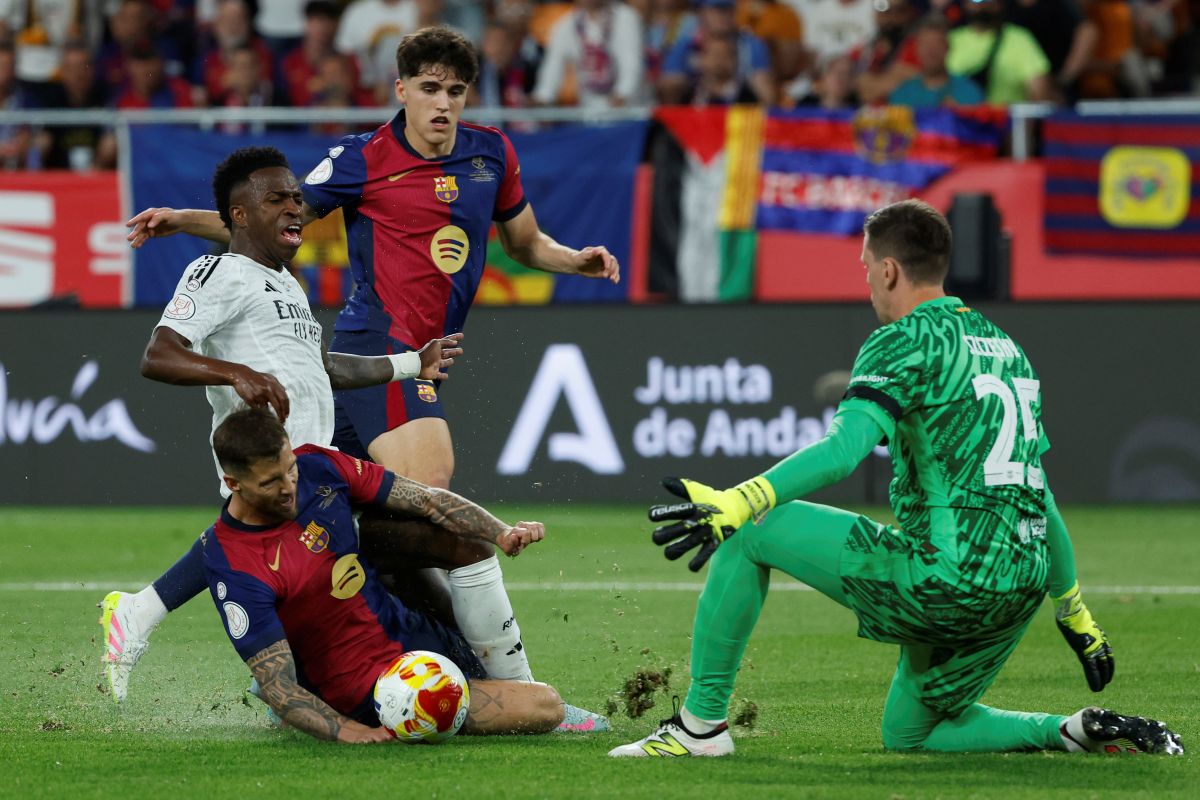 Real Madrid's Vinicius Junior, second left, fights for the ball with Barcelona's goalkeeper Wojciech Szczesny, right, Barcelona's Inigo Martinez, left, and Barcelona's Pau Cubarsi during the Spanish Copa del Rey final soccer match between Barcelona and Real Madrid at Estadio de La Cartuja stadium in Seville, Spain, Saturday, April 26, 2025. (AP Photo/Joan Monfort)