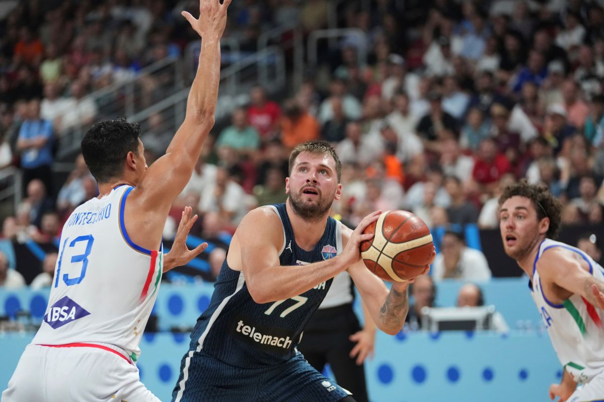 Slovenia's Luka Doncic, centre, tries to shoot while defended by Italy's Simone Fontecchio during the Eurobasket, European Basketball Championship round of 16 match between Italy and Slovenia at the Riga Arena in Riga, Latvia, Sunday, Sept. 7, 2025. (AP Photo/Sergei Grits)