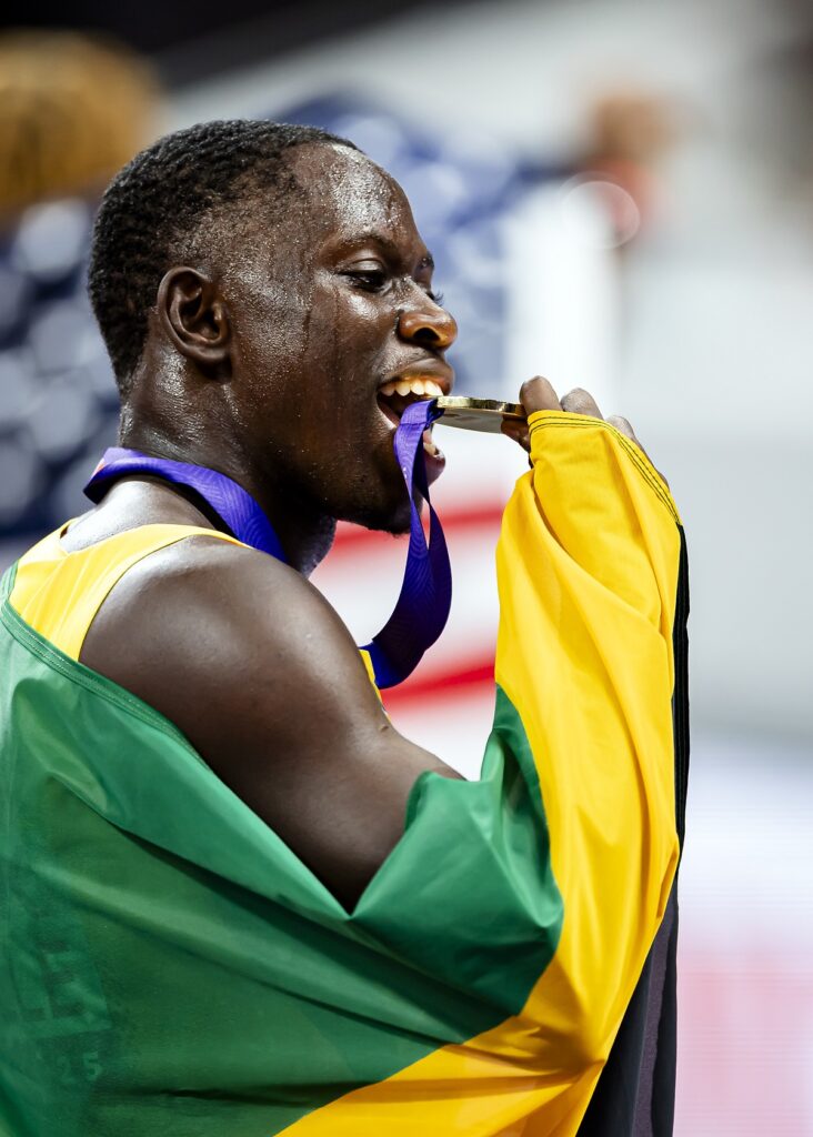 Jamaica's Oblique Seville bites his gold medal after winning the men's 100 meters final, at the World Athletics Championships in Tokyo, Sunday, Sept. 14, 2025. (Michael Buholzer, Keystone via AP)