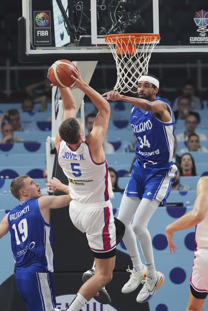 Serbia's Nikola Jovic, centre, tries to shoot while defended by Finland's Jacob Grandison during the Eurobasket, European Basketball Championship round of 16 match between Serbia and Finland at the Riga Arena in Riga, Latvia, Saturday, Sept. 6, 2025. (AP Photo/Sergei Grits)