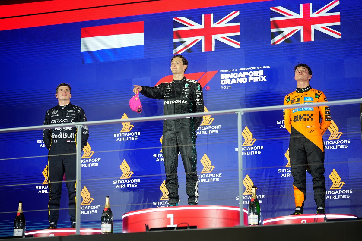 First position winner Mercedes driver George Russell of Britain, center, celebrates on the podium with second place winner Red Bull driver Max Verstappen of the Netherlands, left, and third position winner McLaren driver Lando Norris of Britain during the Singapore Formula One Grand Prix at the Marina Bay Street Circuit in Singapore, Sunday, Oct. 5, 2025. (AP Photo/Vincent Thian)