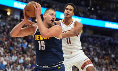 Denver Nuggets center Nikola Jokic, left, pulls in a rebound as Phoenix Suns forward Oso Ighodaro, right, defends in the first half of an NBA basketball game Saturday, Oct. 25, 2025, in Denver. (AP Photo/David Zalubowski)