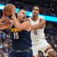 Denver Nuggets center Nikola Jokic, left, pulls in a rebound as Phoenix Suns forward Oso Ighodaro, right, defends in the first half of an NBA basketball game Saturday, Oct. 25, 2025, in Denver. (AP Photo/David Zalubowski)
