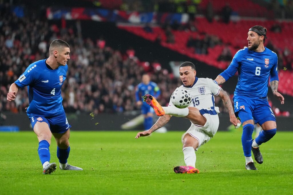 England's Morgan Rogers misses the ball between Serbia's Nikola Milenkovic, left, and Nemanja Gudelj during a World Cup qualifier group K soccer match between Serbia and England in London, Thursday, Nov. 13, 2025. (AP Photo/Kirsty Wigglesworth)