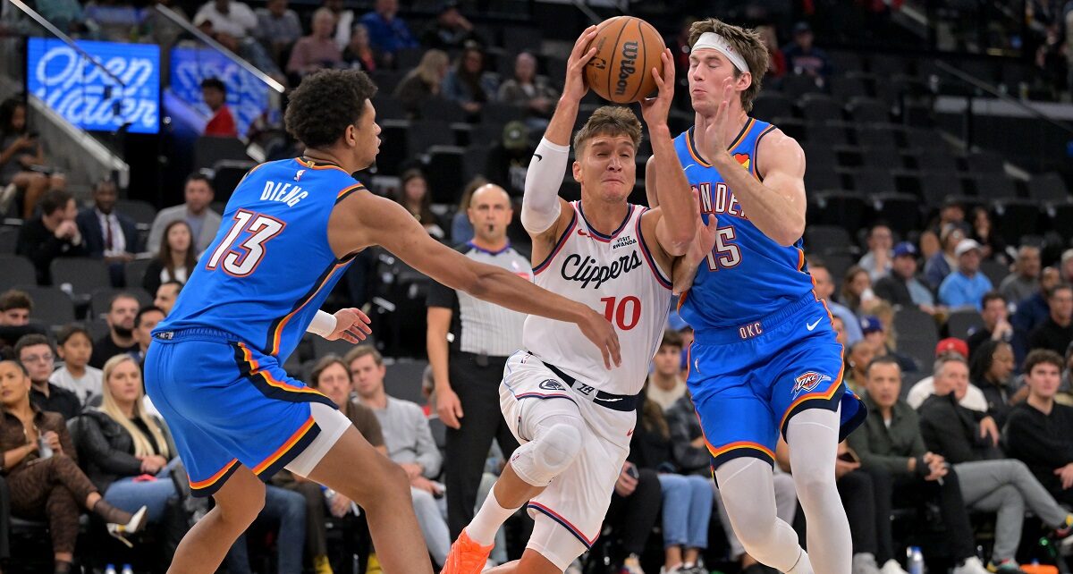 Los Angeles Clippers guard Bogdan Bogdanovic (10) drives past Oklahoma City Thunder forward Ousmane Dieng (13) and Thunder center Branden Carlson during the second half of an NBA basketball game Tuesday, Nov. 4, 2025, in Los Angeles. (AP Photo/Jayne Kamin-Oncea)